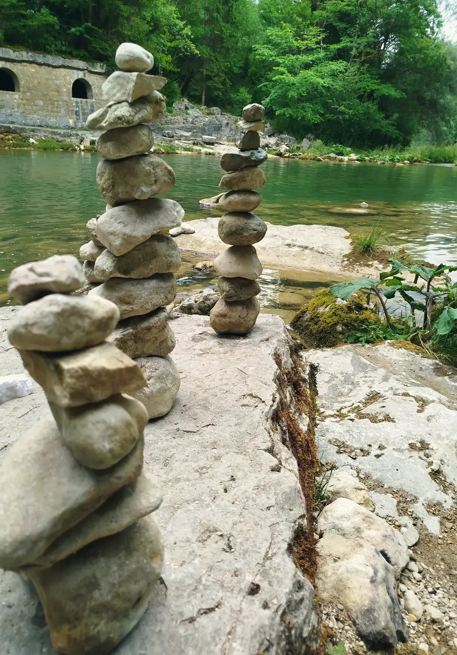 Stone cairns by the green Orbe, below the old arches in the gorge